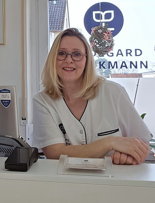 Fußpflege Cosmore Elze Die Fußpflegerin Beate Jehle steht hinter ihrem Tresen und lächelt.